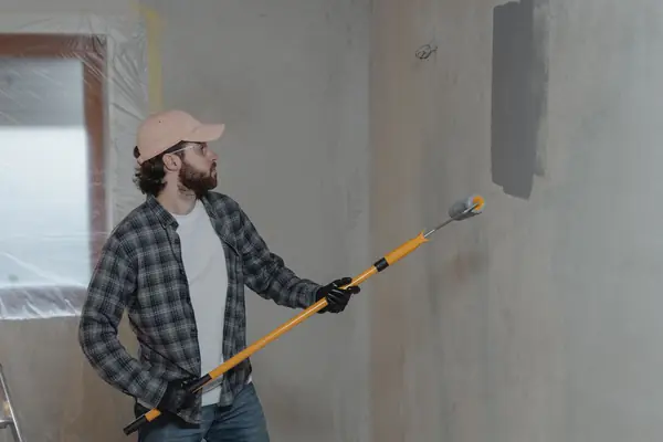 Painter rolling grey paint onto an interior wall in Abilene