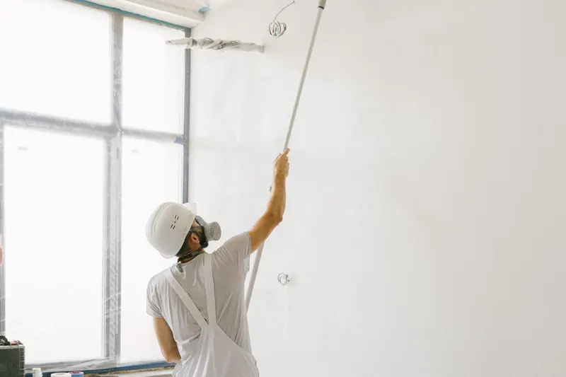 Interior painting in Abilene: professional painter in whites rolling paint onto a wall